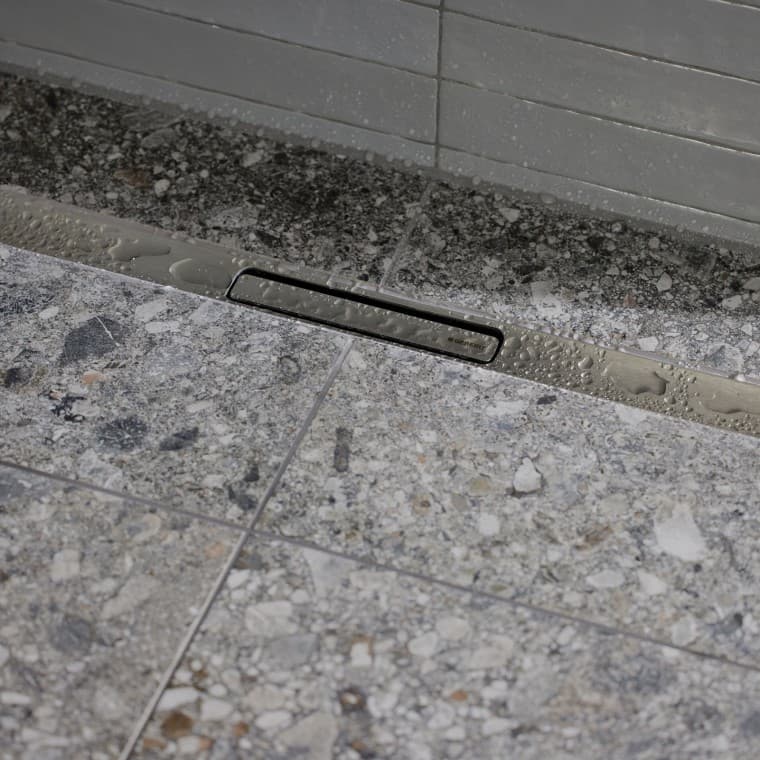 Vesi valuu viemäriin tyylikkään, ruostumattomasta teräksestä valmistetun muodon kautta. Vesi valuu viemäriin tyylikkään, ruostumattomasta teräksestä valmistetun muodon kautta.