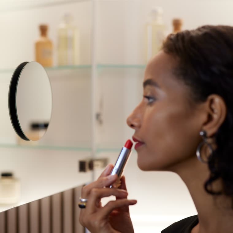 Nainen meikkaamassa suurennuspeilin avulla Nainen meikkaamassa suurennuspeilin avulla
