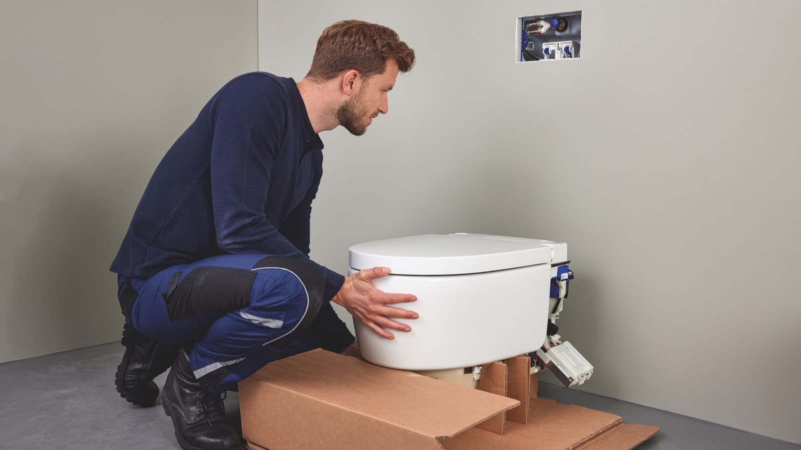 Ammattiasentaja asentamassa Geberit AquaClean Sela -pesu-wc-istuinta Ammattiasentaja asentamassa Geberit AquaClean Sela -pesu-wc-istuinta